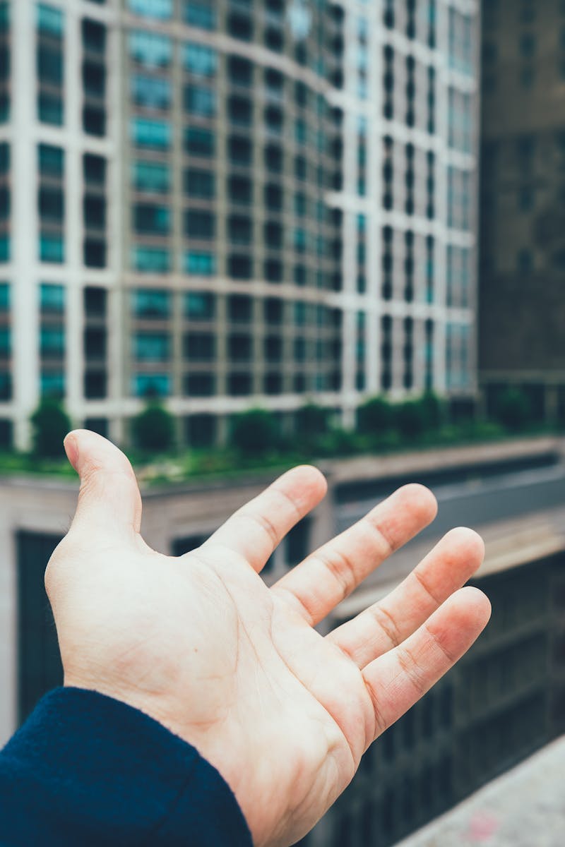 A hand reaching towards modern skyscrapers, reflecting the urban vibe.